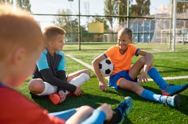 Gençlerin futbol takımı antrenmandan sonra ya da maçtan sonra futbol sahasında konuşuyor.