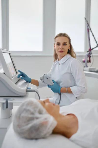 現代の医療事務所でレーザーマシンで働く女性美容師の肖像画 専門化粧品の概念 — ストック写真