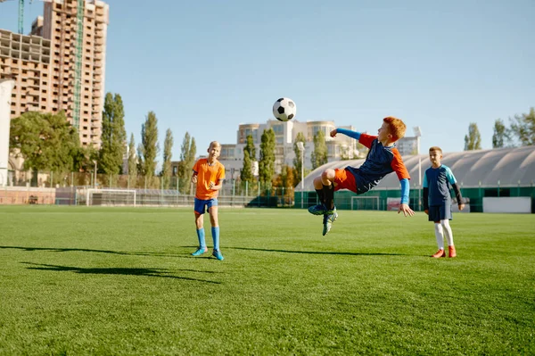 ジュニアフォワードはサッカーの試合に参加して足でボールをキックするジャンプします 学校サッカーチームスポーツゲーム — ストック写真
