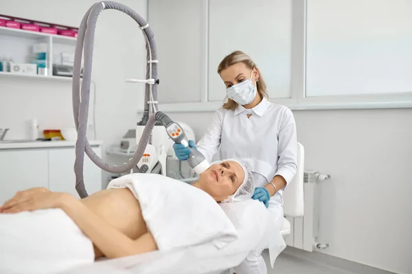 美容医師は 女性のクライアントのためのフェイス機器マッサージを行います 審美的な顔療法の概念 — ストック写真