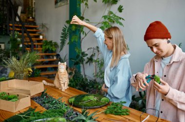 Genç mutlu aile dekoratörü profesyonel mesleği. Kadın ve erkek rahat bir çiçekçide çalışıyor.