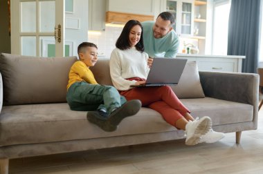 Evde mutlu bir aile ve annem bilgisayarda çalışıyor. Karı koca kucaklıyor, oğul ilgi istiyor. Ebeveynlik ve serbest iş dengesi