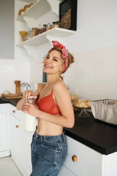 若いです女性でランジェリーオープンAボトルとともにミルクと笑顔でキッチン — ストック写真