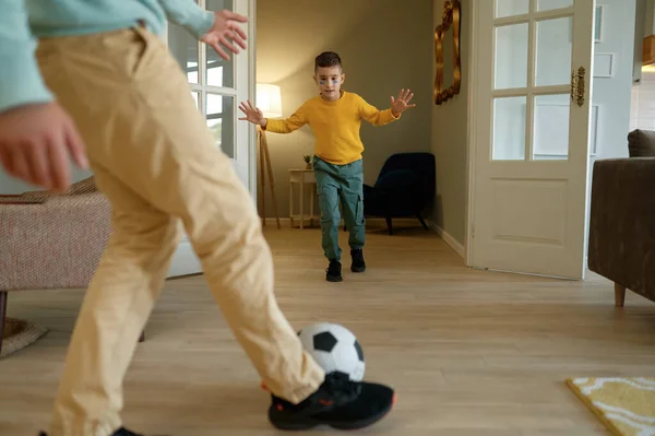 Emotional father and son playing football with ball at home living room. Leisure activity, happy family and game practice