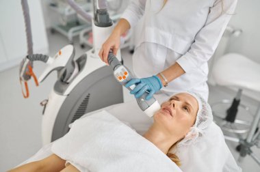 Bayan müşteri için yüz masajı yapan güzellik doktoru. Estetik yüz terapisi kavramı