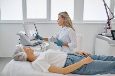 Modern tıp ofisinde lazer makinesiyle çalışan kadın kozmetik uzmanının portresi. Profesyonel kozmetoloji kavramı