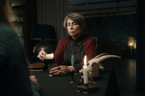 Mature Witch Reading Spell Client Using Candle — Stock Photo, Image