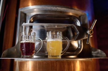 Freshly made craft light and dark beer in glass mug standing on barrel. Brewery concept, small business