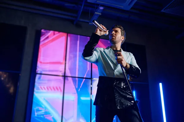 男歌手手持话筒站在舞台上表演的低视角镜头 — 图库照片