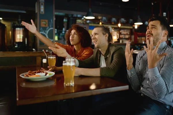 Multiracial football fans frustrated by failed bad team sport result drinking beer in pub restaurant together
