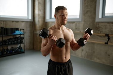 Sportive man holding weights workout with dumbbells in gym. Strength and sport motivation