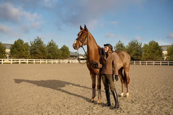 A horse trainer with her stallion outdoors spending time at countryside farm. Horsewoman on rancho
