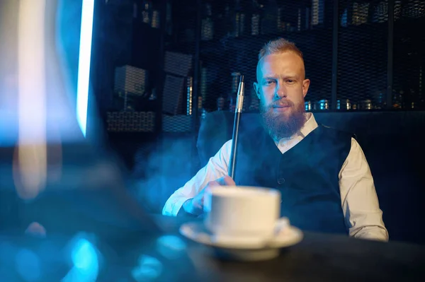 Handsome Bearded Man Sitting Table Smoking Hookah While Drinking Coffee — Fotografia de Stock