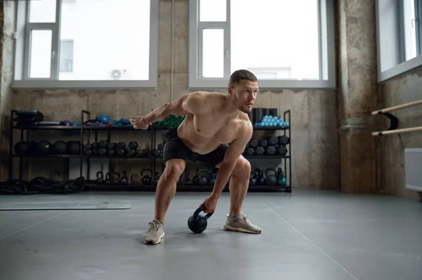 ジムでの運動中に重いケトルベルを持ち上げるフィット感と筋肉の男 ハードコア筋肉トレーニング — ストック写真