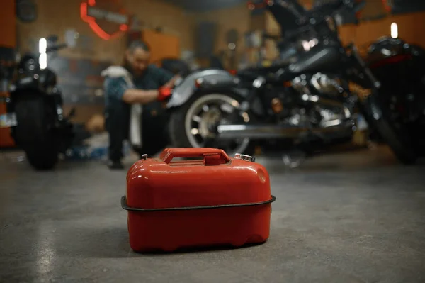 オートバイのガレージで燃料キャニスターに選択的な焦点 成熟したバイカー修理オートバイ上のぼやけた背景 — ストック写真