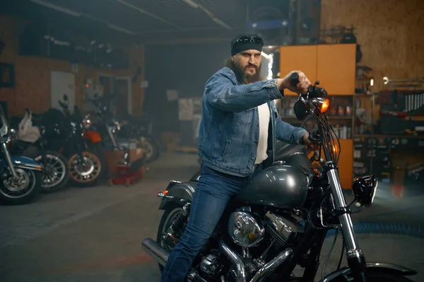 ガレージの店で新しいバイクをテストするハンサムな髭の男 自動車店で新しい車を選ぶバイカー — ストック写真