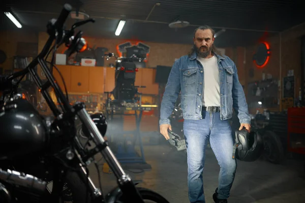 ガレージのワークショップでオートバイを見てひげそり残忍なバイカーの肖像画 バイクサービス — ストック写真