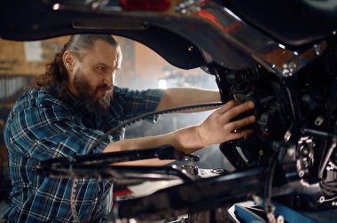 Motosiklet motoru tamir eden bir adam. Garaj tamirhanesinde çalışan bir tamirci. Motosiklet tamir hizmeti kavramı