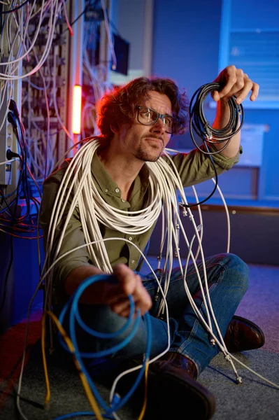 狂ったコンピュータエンジニアは サーバールームのワイヤとケーブルに包まれました 混乱した技術サポートワーカーは インターネット接続を復元しようとして頭の上で髪を引き裂く叫び — ストック写真