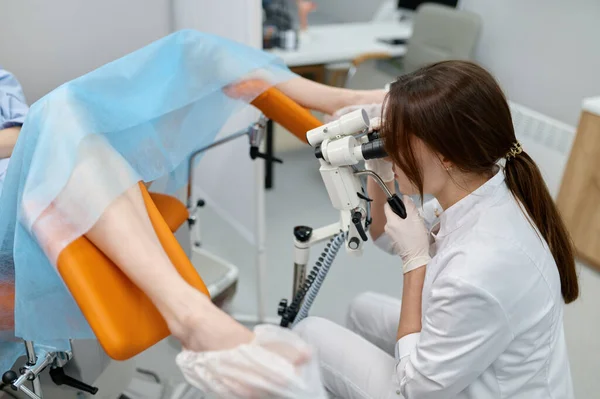 用妇科显微镜对坐在椅子上的女病人进行妇科检查的医生 — 图库照片