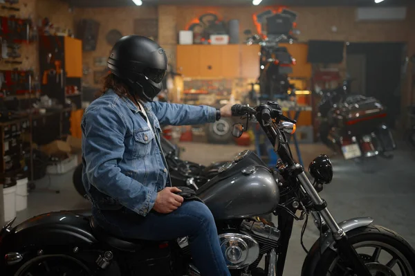 男性バイカーで保護ヘルメットに座っているオートバイのテストガレージのインテリア上の新しい車 — ストック写真