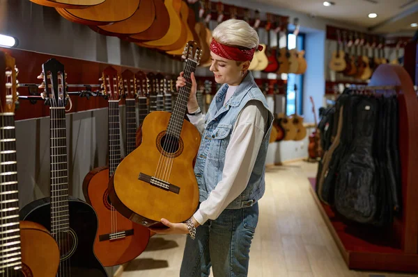 楽器店でアコースティックギターを選ぶ若いヒップスター女性 ミュージカルストアでの女性の購入 — ストック写真