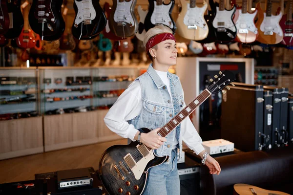 若いですヒップスター女性音楽家の肖像とともに電動ギター専門店の上に立つ — ストック写真