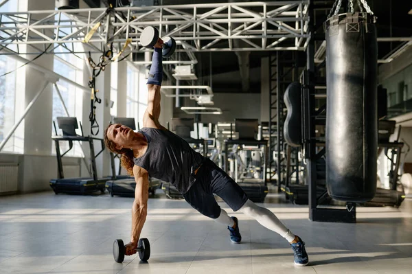 強力な完璧なボディと腕の力を示す重い重みのダンベルと筋肉スポーツマンのトレーニング スポーツジムインテリア — ストック写真