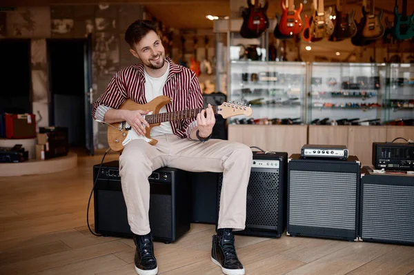 音楽店でのオーディオ機器の購入 アンプに接続されたギターを演奏しながら音を楽しむ男 — ストック写真