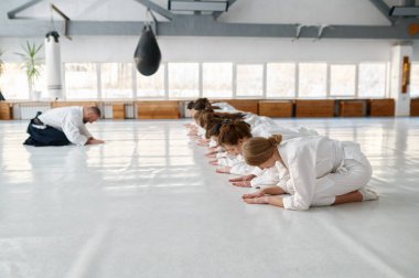 Genç bir aikido öğrenci grubu ve usta ders başında birbirlerini selamlıyorlar. Kadınlar için dövüş sanatları eğitimi kursu