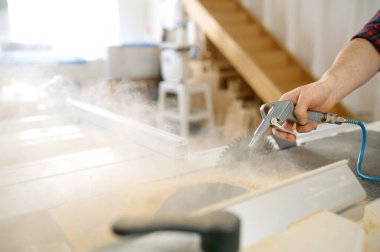 Marangoz ahşap ahşap talaşını temizliyor. Yakından bakınca, su hortumunu hortumla tutuyor. Marangozluk atölyesi, aptalca bir hobi.