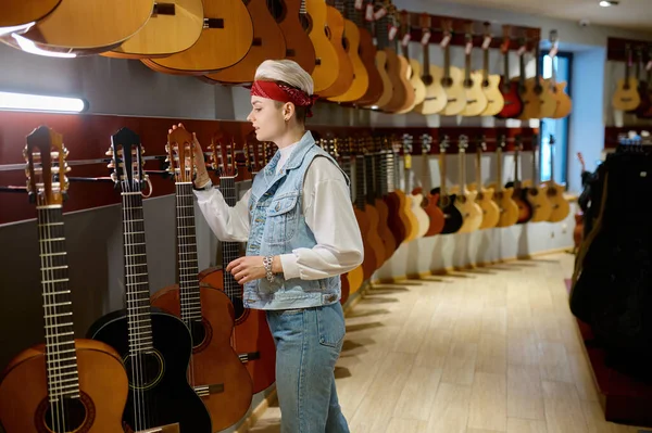 楽器店でアコースティックギターを選ぶ若いヒップスター女性 ミュージカルストアでの女性バイヤー — ストック写真