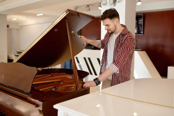 Ladenkonzept Für Musikinstrumente Junger Mann Schaut Auf Stimmtasten Flügel Unter — Stockfoto