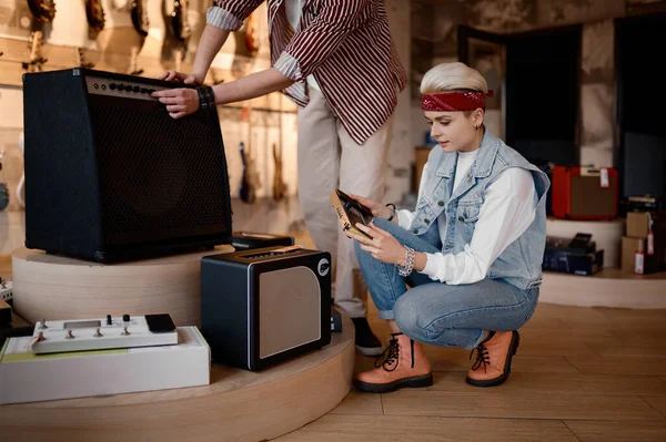 プロの音楽店でアンプハイエンドステレオ機器を購入する若い自信のある男性と女性のミュージシャン — ストック写真