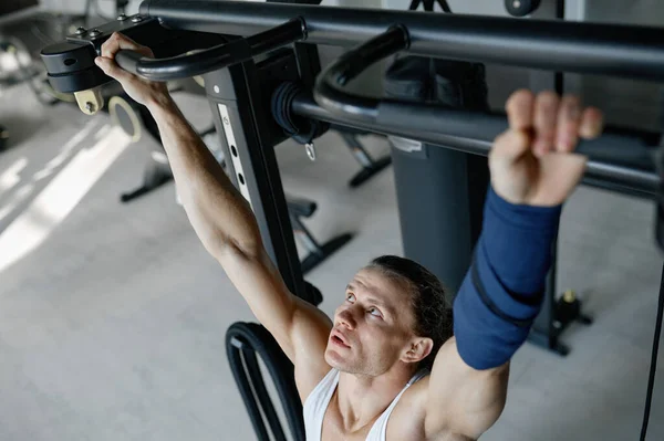 ジム機器を使用して体重の強いスポーツマンのトレーニングでトップビュー ボディービルのためのワークアウトをプルアップして運動体を持つ男 — ストック写真