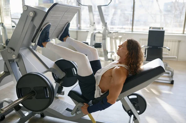关于年轻健美运动员在健身房锻炼腿肌肉的侧视图 硬体全身训练的概念 — 图库照片