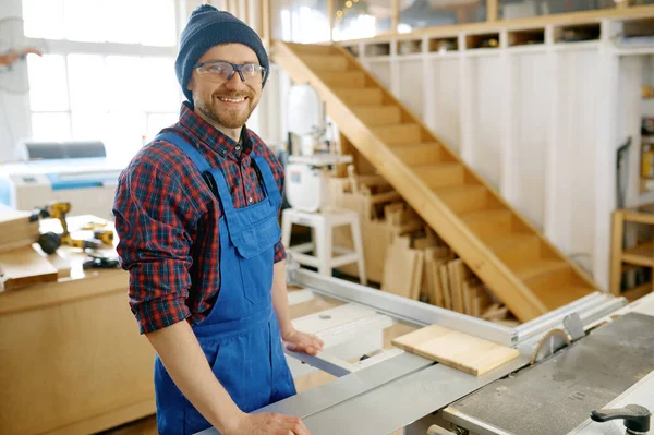穿着工作服和护目镜的快乐的木匠站在工作场所准备在圆锯工作台上工作的画像 — 图库照片