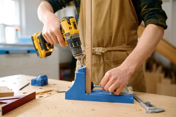 人工木匠用专业的电器设备在木板上打孔 木工演播室男工手工缝制的衣服 — 图库照片