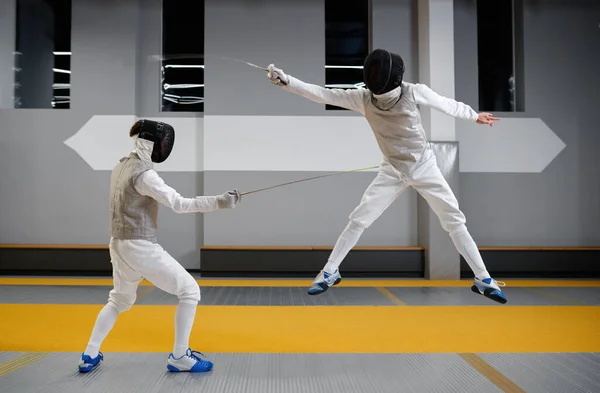 两名击剑选手在职业武术学校的训练课上打斗 剑客跳跃着试图躲避攻击 — 图库照片