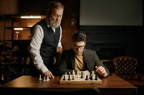 ゲームのルールを説明するチェスをする若い男を教える上級男性 教育レジャー — ストック写真