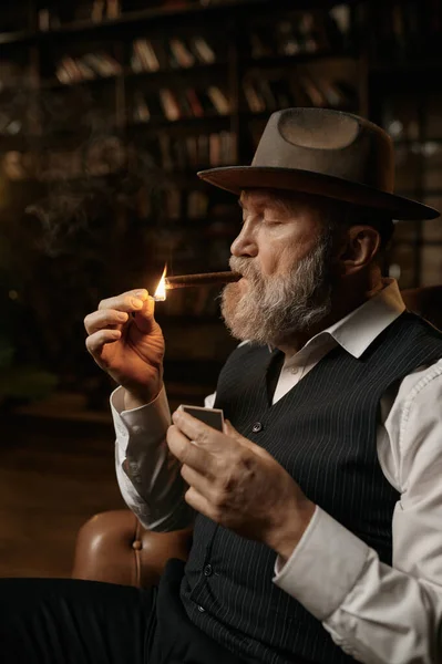 Элегантный Пожилой Джентльмен Закуривает Сигару Сидя Кресле Портрет Стильного Мужчины — стоковое фото