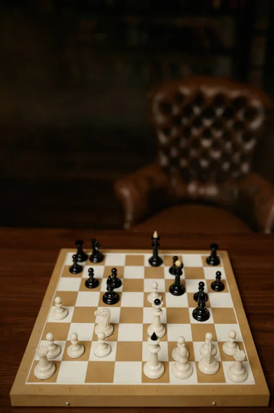 Jogadores de xadrez masculinos no tabuleiro, movimento de vista superior  branca. dois jogadores de xadrez começam o torneio intelectual dentro de  casa. tabuleiro de xadrez na mesa de madeira
