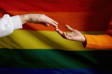 Lezbiyen çiftin diğer elini gökkuşağı gurur bayrağına uzatıyor. lgbtq cinsiyetler arası hakları kavramı