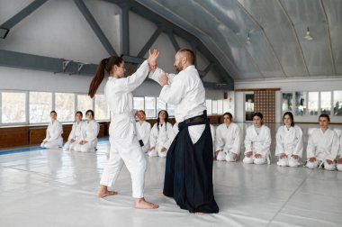 Diğer genç öğrencilere aikido tekniği gösteren genç bir bayan öğretmen. Dövüş okulunda grup eğitimi.