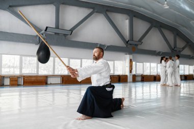 Kendinden emin ve güçlü bir aikido ustası bokken Japon kılıcıyla dövüş pozisyonunda duruyor.