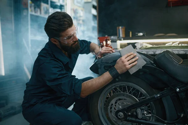 年轻男工在修理时戴着防护眼镜 从旧油漆中取出摩托车 — 图库照片
