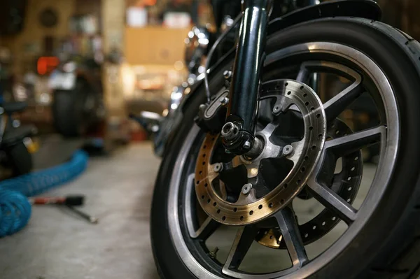 Closeup view on motorcycle front wheel in workshop. Motorbike showroom for sale or repair garage service concept