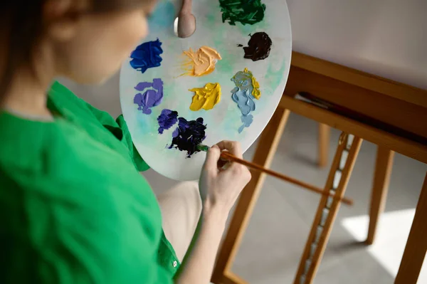 アーティストの基本的なツールコンセプト 筆や木の板で油絵具からカラーパレットを作る女性の手のクローズアップ — ストック写真