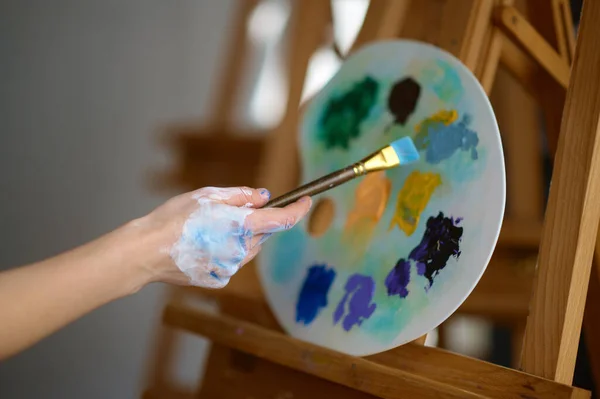画家手拿着画笔在塑料调色板上的油彩混合画上画笔 艺术基本工具和艺术创作过程概念 — 图库照片