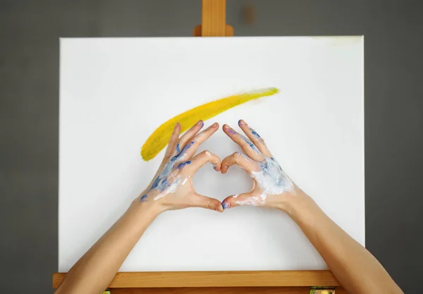 絵のキャンバス上にハート型のサインを作るアーティストの手の構成 愛と芸術と教育の概念を持つ芸術療法 — ストック写真